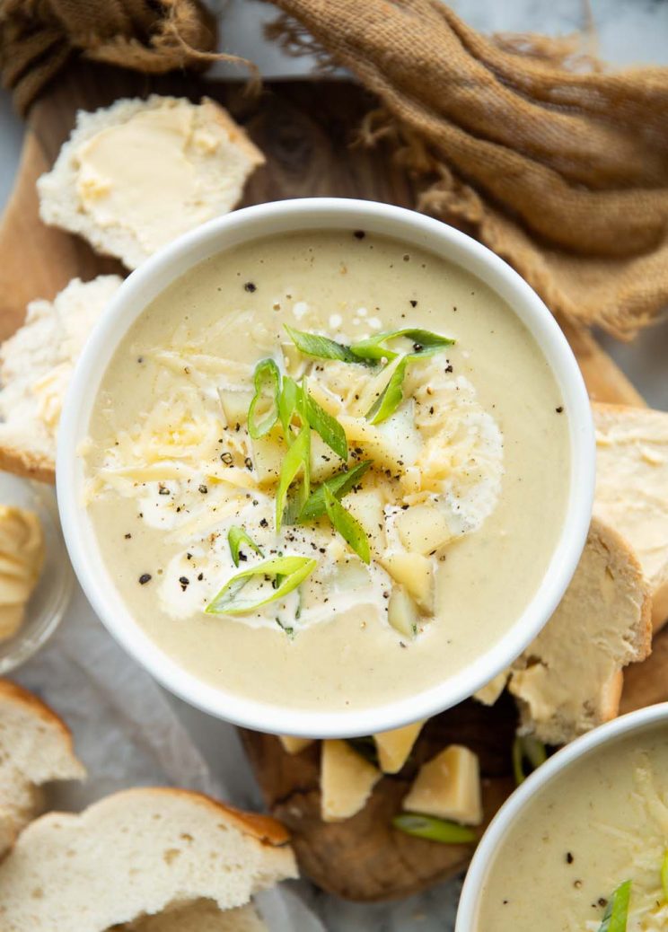 overhead shot of soup surround by buttered bread on chopping board