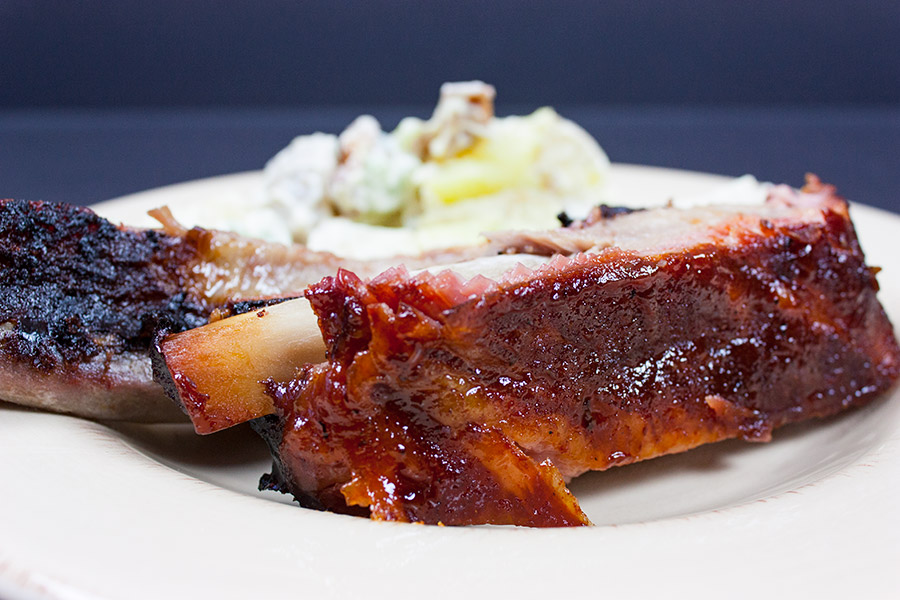 A st. louis style rib on a plate with potato salad