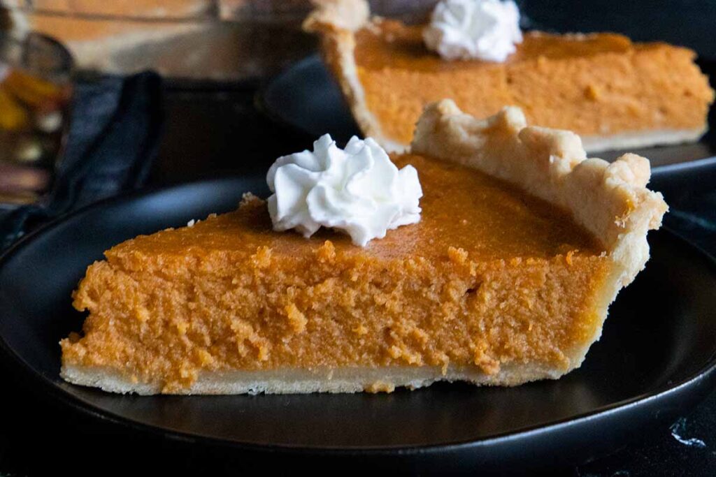 Slices of sweet potato pie on black plates