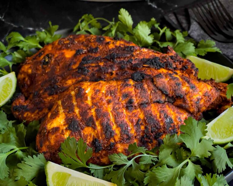 Pechuga asada on a bed of cilantro with limes.