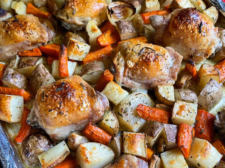 One pan roasted chicken and vegetables in a foil and parchment paper lined baking sheet.