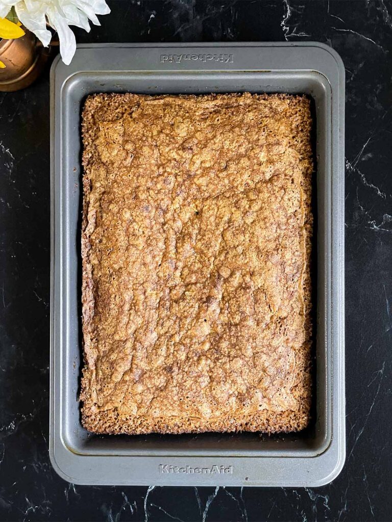 Baked sweet potato cake in a 9x13 baking pan on a dark surface.