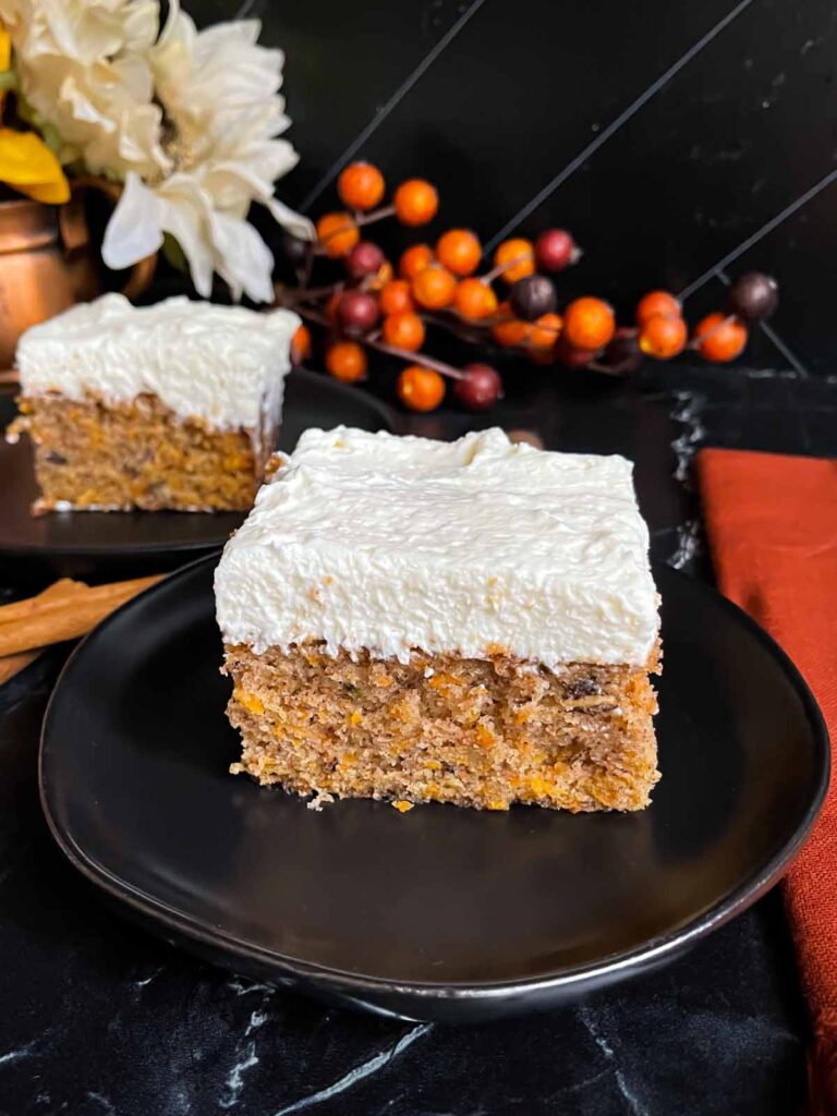 A slice of sweet potato cake on dark plate on a dark surface.