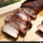 Smoked pork tenderloin on a wooden cutting board.