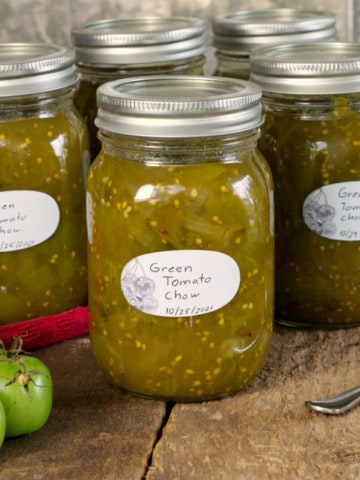 canadian green tomato chow chow in labeled mason jars on a rustic wooden surface