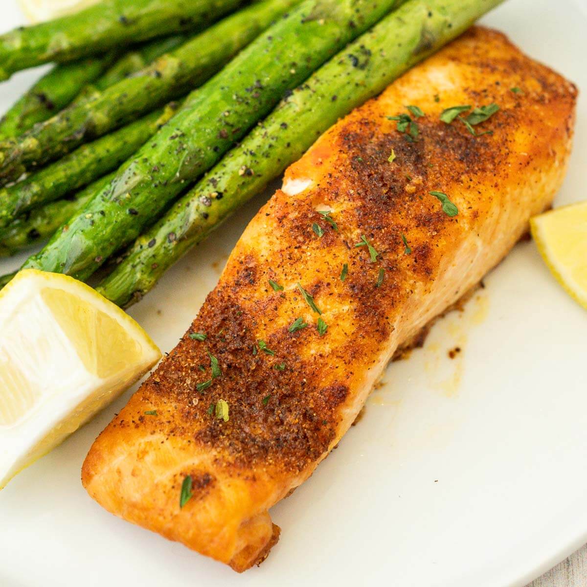 Air fryer Salmon on a plate with asparagus and fresh lemon