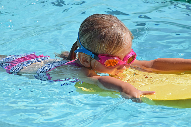 Little girl swimming at an outdoor pool