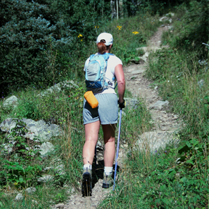 A woman hiker with her back to the camera walks up a mountain trail