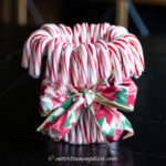 A Christmas ribbon tied around the middle of a DIY red and white candy cane vase