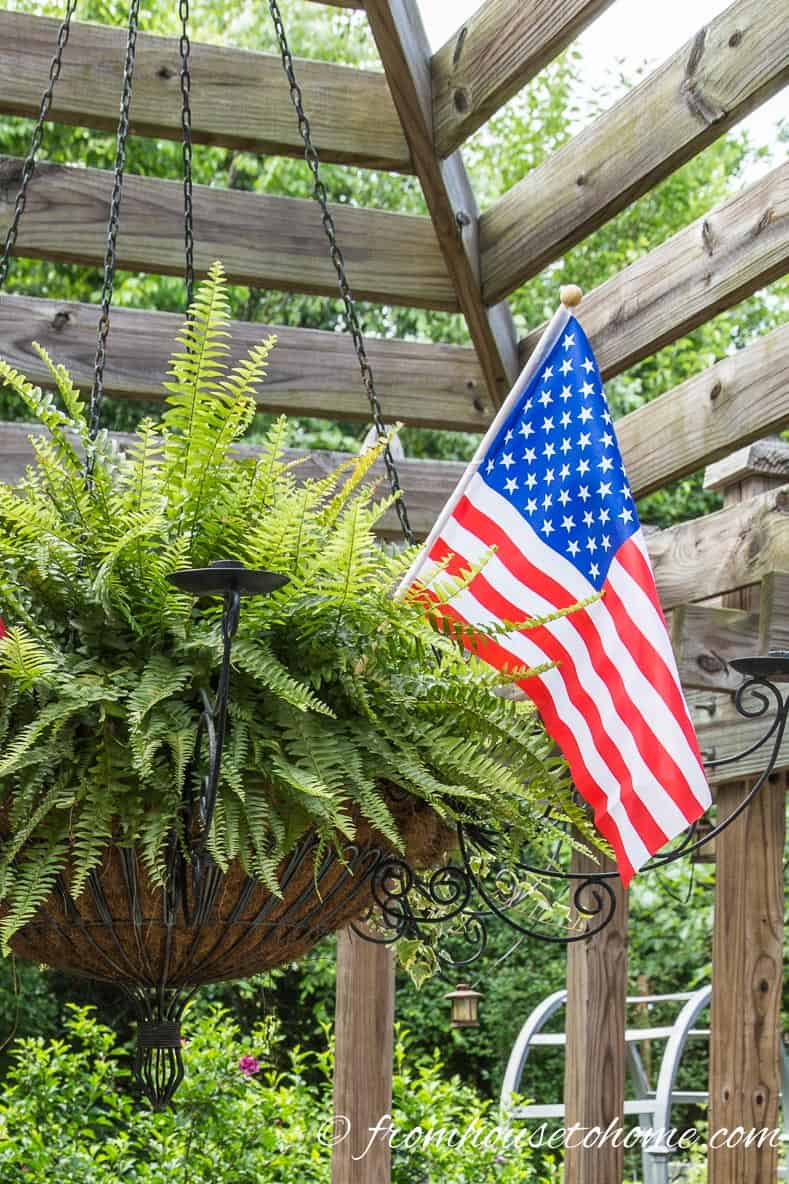 A small American flag in a large hanging pot with a fern