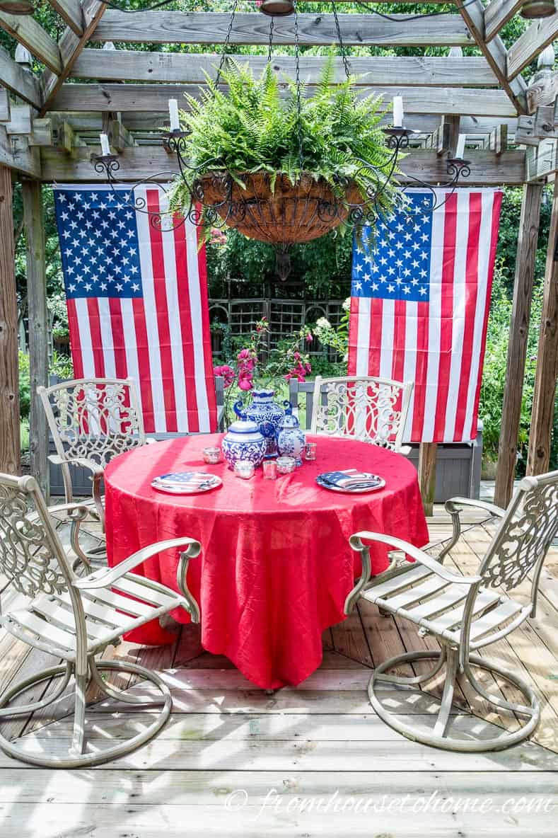 Flags hanging from the side of a gazebo with a table decorated in red, white and blue in front of it