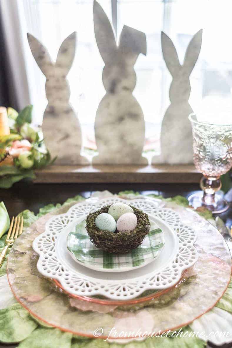 Easter bunny centerpiece behind the pink and green Easter place setting