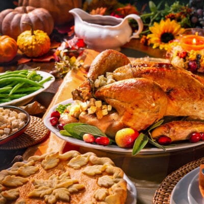 Thanksgiving table with turkey, pie, green beans, gravy and pumpkins