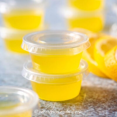 a stack of lemon drop jello shots in shot cups with lids