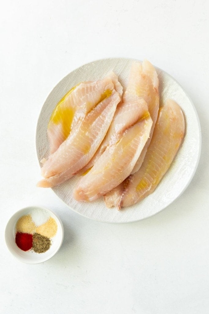 Oil drizzled on tilapia with seasoning put together in a bowl