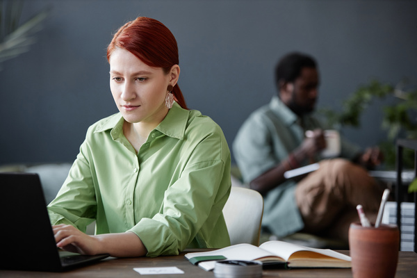 A Woman in a Green Shirt Sitting in Front of a Laptop Computer