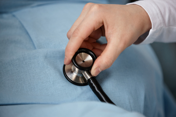 A Person Using a Stethoscope on a Pregnant Woman