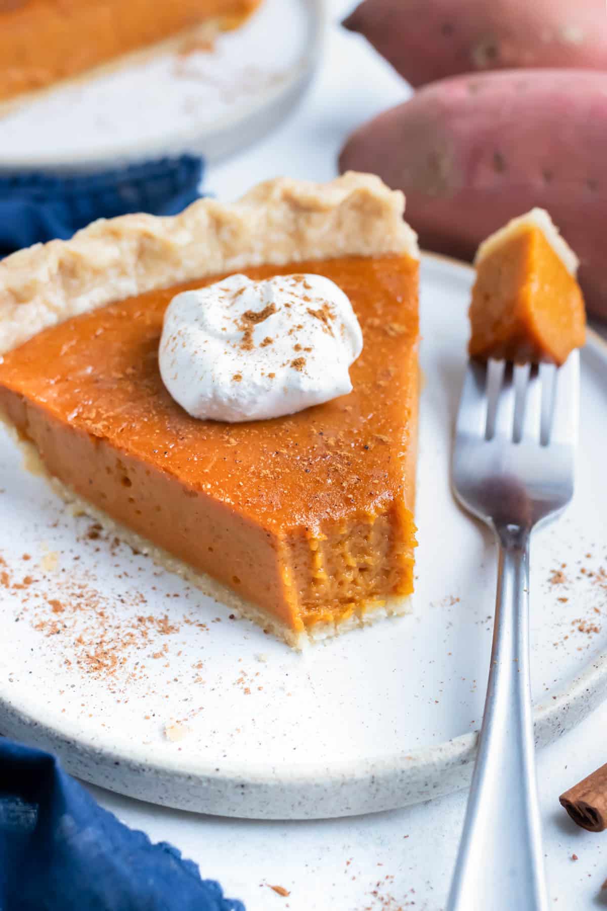 Sweet potato pie served on a plate with a dollop of whipped cream on top.