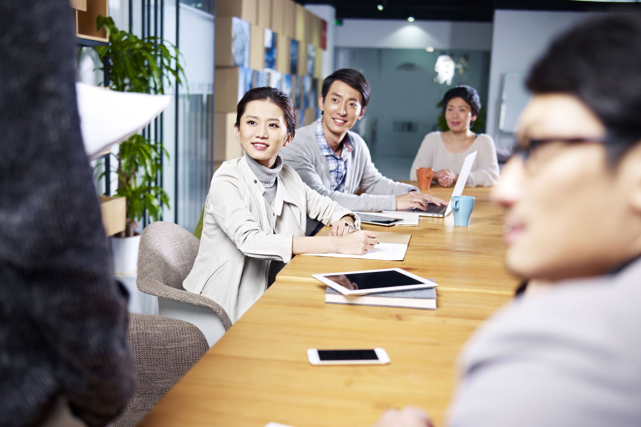 Team of young Asian entrepreneurs meeting in office