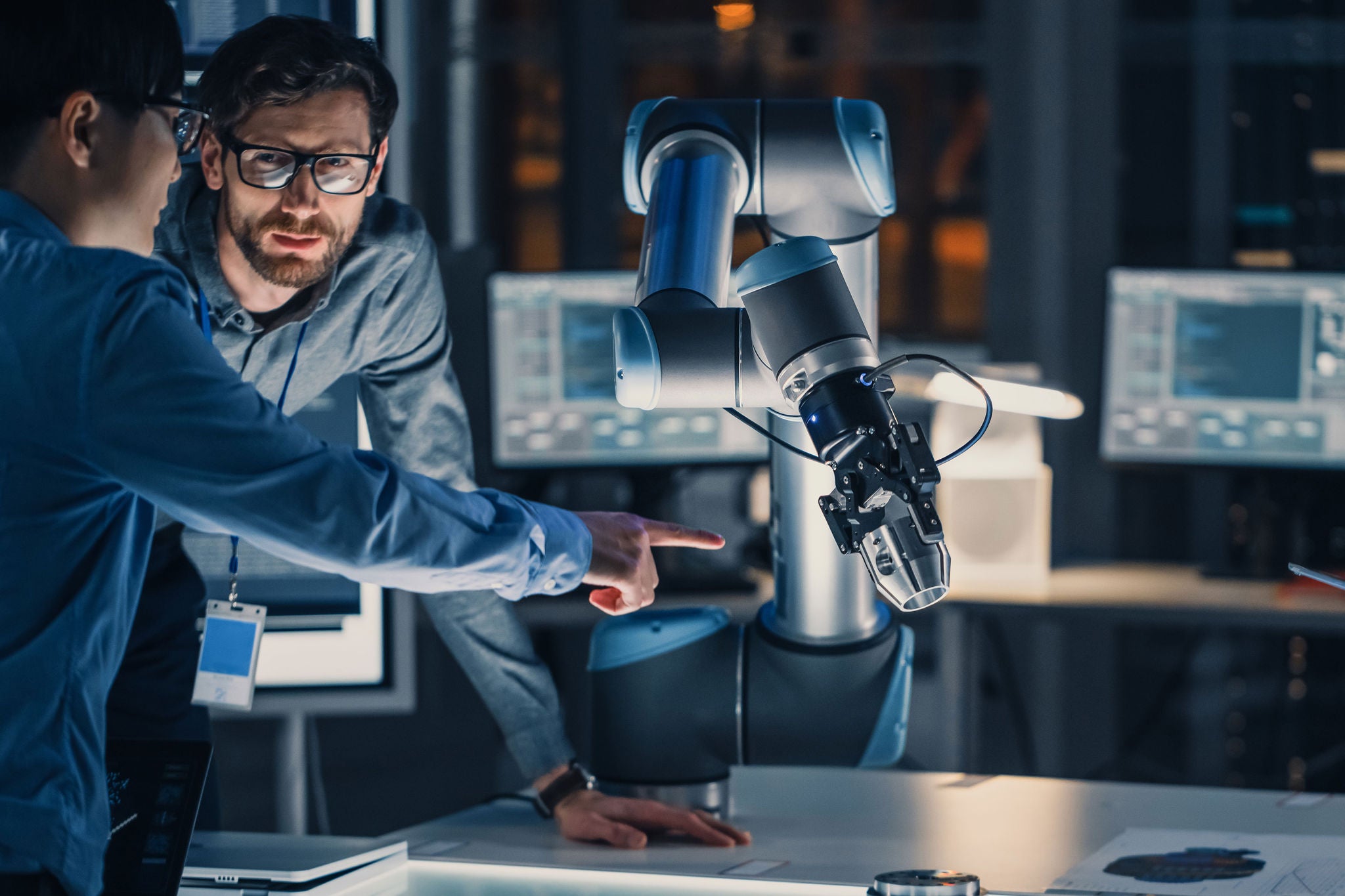 Two technologists in discussion next to machine