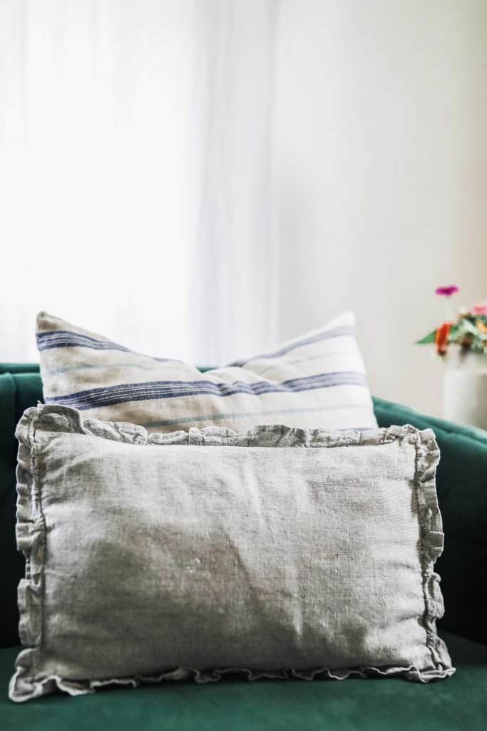 ruffle pillow cover on a green couch with a stripped pillow behind it