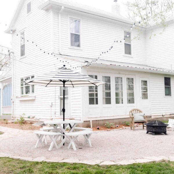 pea gravel patio with a flagstone boarder in the back of a white farmhouse