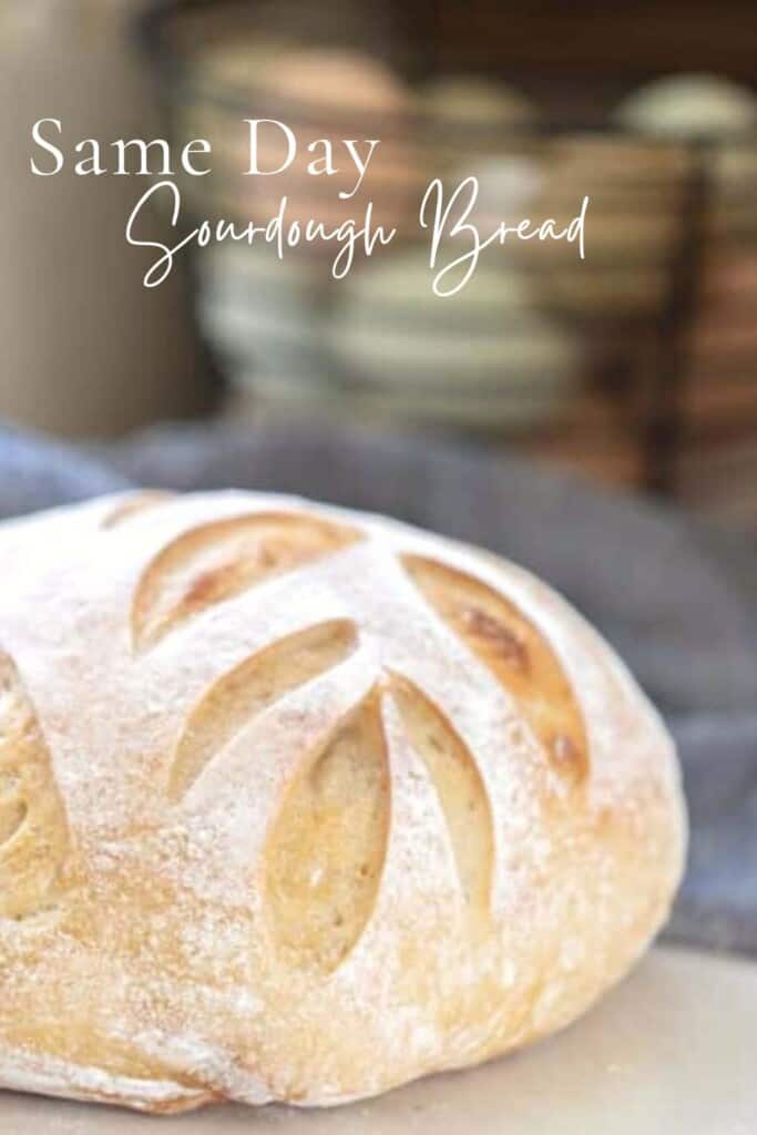 loaf of same day sourdough bread with a leaf scoring pattern on a white counter