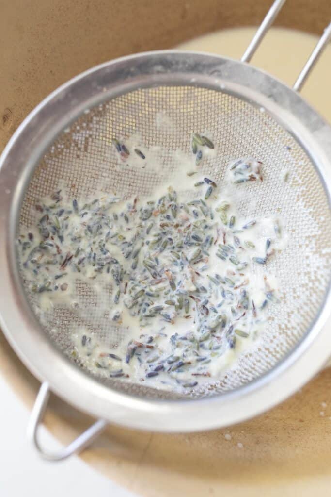 Straining lavender cream  with a fine mesh strainer into a pot.