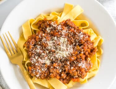 A bowl of Pappardelle Bolognese topped with parmesan cheese