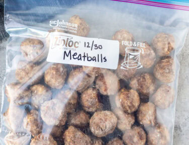 Frozen meatballs in a Ziplock freezer bag that has been labeled and dated and ready to be reheated.