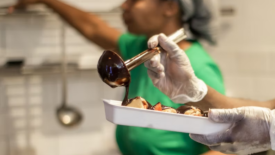 man and woman in foodservice kitchen with gloves and hairnets