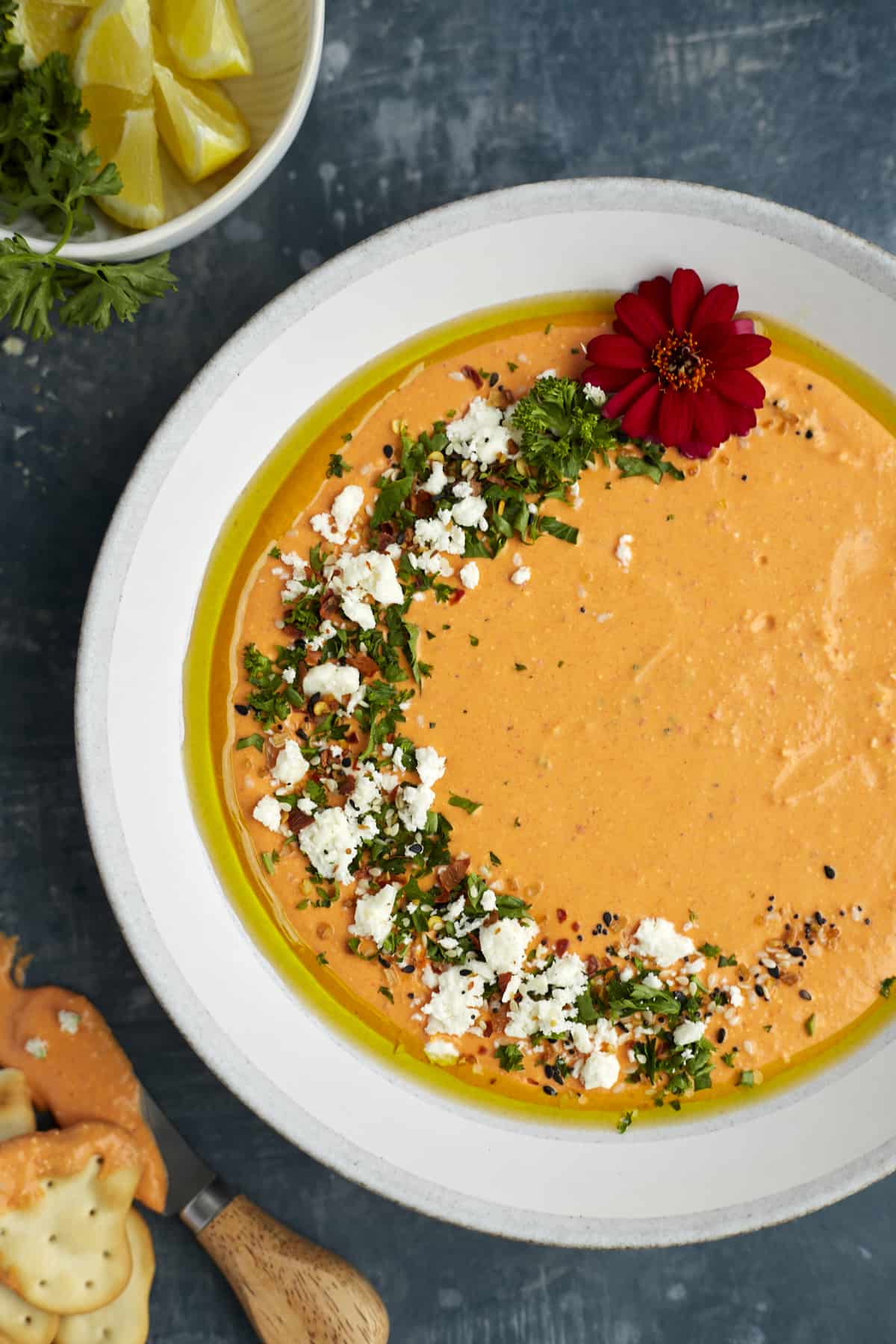 Plated roasted red pepper whipped feta topped with olive oil and feta.