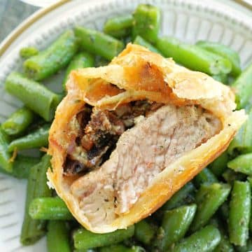 pork wellington sliced in a half and plated with green beans