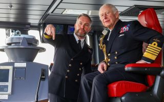 Commanding Office Captain Will Blackett shows King Charles the controls on the HMS Prince of Wales