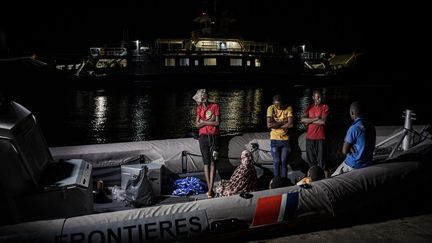 Un ferry passe à côté d'immigrés clandestins comoriens stationnés sur un bateau de la Police de l'air et des frontières (PAF) française amarré à Mayotte. Ceux-ci tentaient de rejoindre l'île française, le 24 mai 2023. (PHILIPPE LOPEZ / AFP)