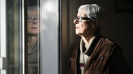 Une femme regarde par la fenêtre de chez elle, à Toulon (Var), le 30 décembre 2023. (MAGALI COHEN / HANS LUCAS / AFP)