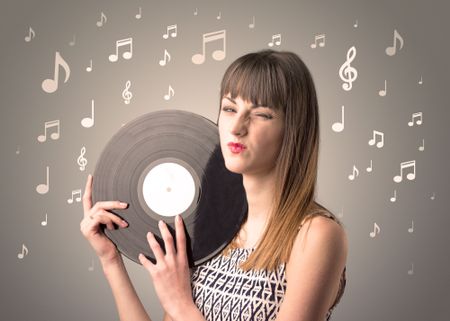 Young lady holding vinyl record on a brown background with musical notes behind her