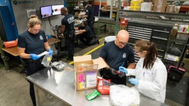 Customs inspectors look at the contents of a package at an airport inspection station.