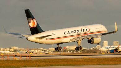 A blue-tailed Cargojet freighter touches down on the runway amid the glow of the afternoon sun.