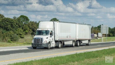 a white tractor pulling two white pup trailers