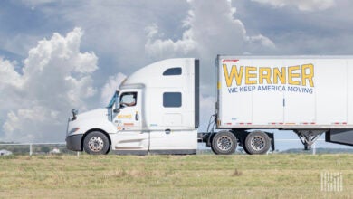 sideview of a parked Werner tractor-trailer with a driver