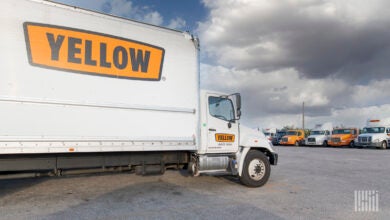 Yellow trucks, tractors and trailers parked at a terminal