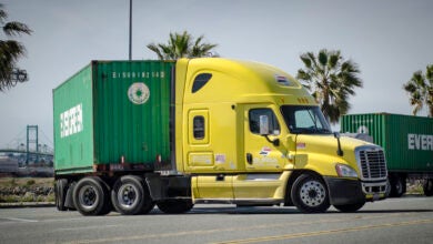 A Yellow sleeper cab pulling an Evergreen ocean container