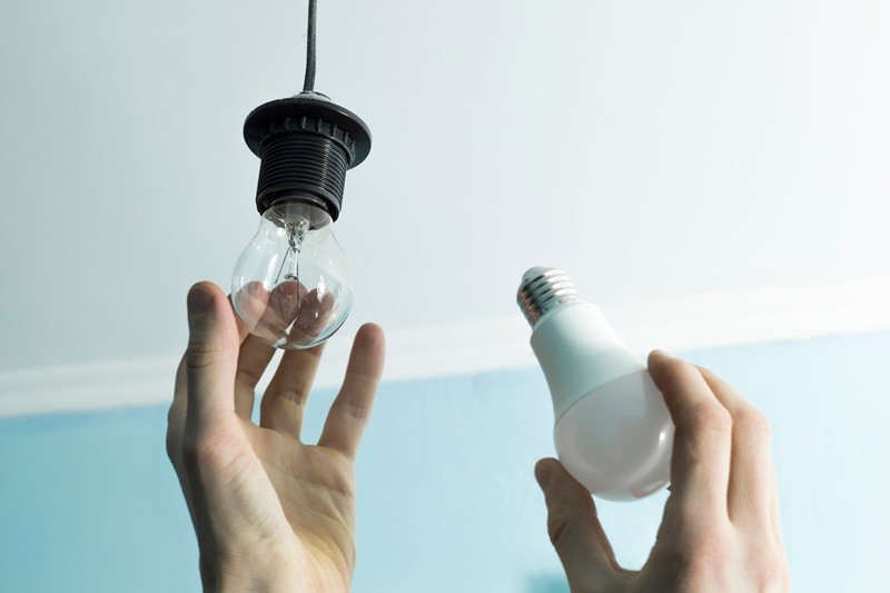 Incandescent lamp is changed to LED light by the hands of a man.