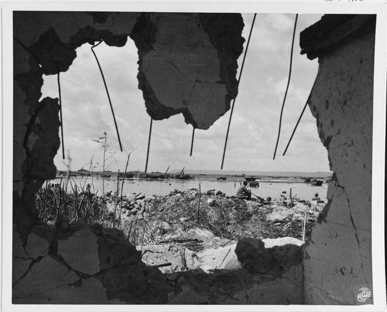 View of part of the Southern Assault Beach, from a ruined building in July 1944. The Orote Peninsula is in the distance. Note machine gun crew in right center.