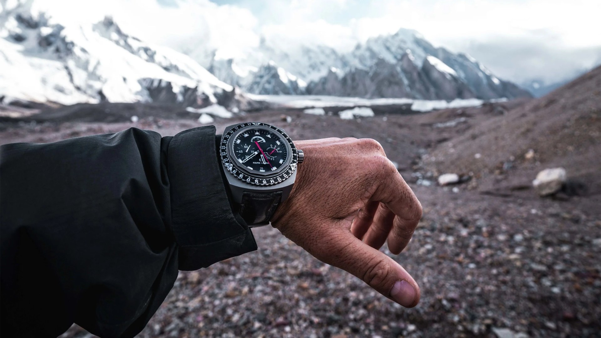 man wearing watch on wrist with mountains in the background