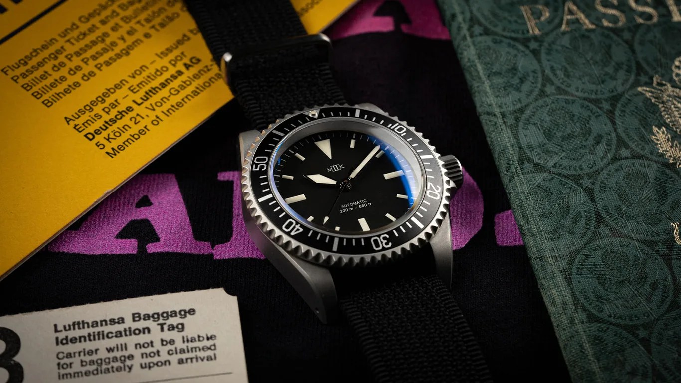 a mkii milsub style dive watch next to an old passport