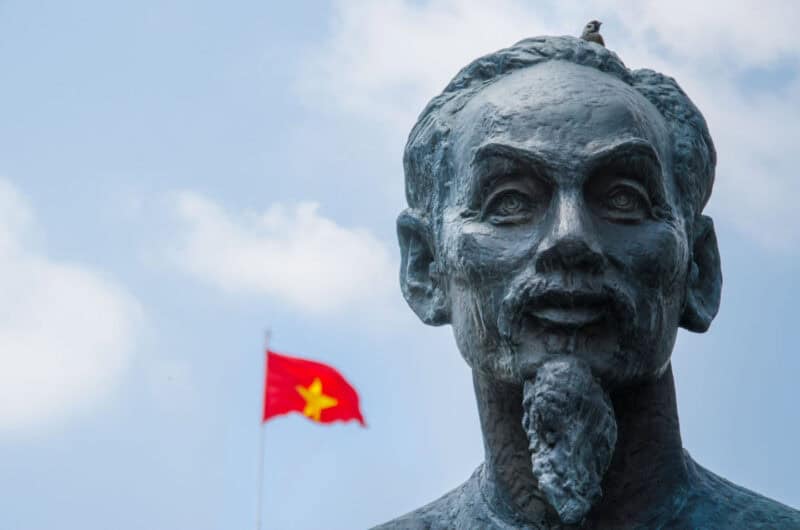 Ho Chi Minh Statue with Vietnam flag blowing in the background 