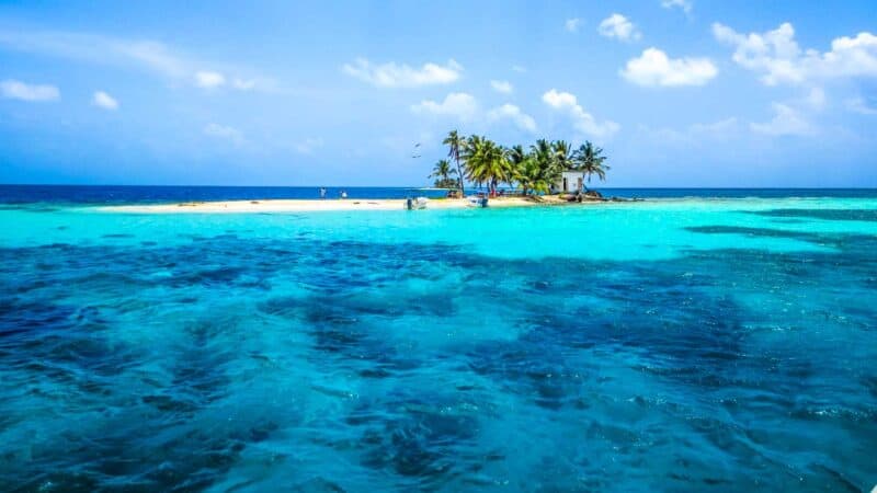 Bright blue water in front of a small island Silk Caye which is one of the best beaches in Belize