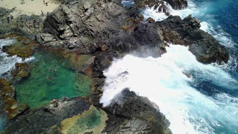 Large wave crashing of the edge of the rock wall of the Natural Pool Aruba